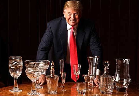 A man in suit and tie sitting at a table with glasses.