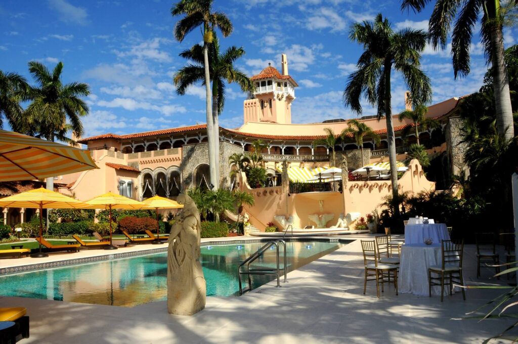 A pool with palm trees and a building in the background.